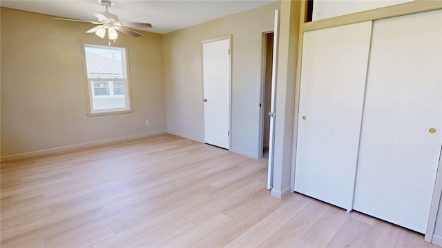 unfurnished bedroom featuring baseboards, ceiling fan, a closet, and light wood-style flooring