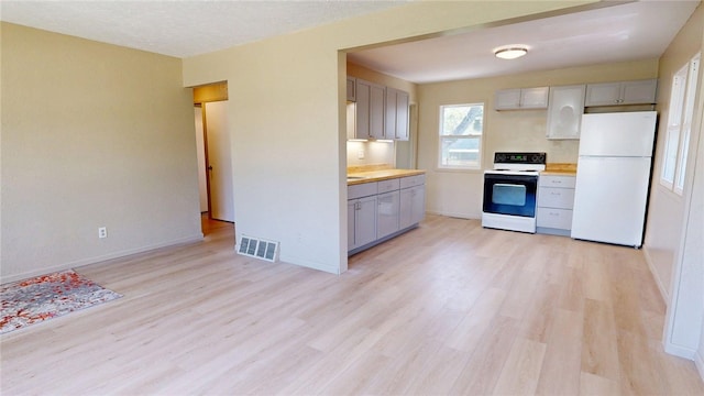 kitchen with gray cabinets, visible vents, freestanding refrigerator, electric stove, and light wood-style flooring