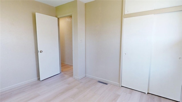 unfurnished bedroom with visible vents, baseboards, a closet, and light wood-type flooring