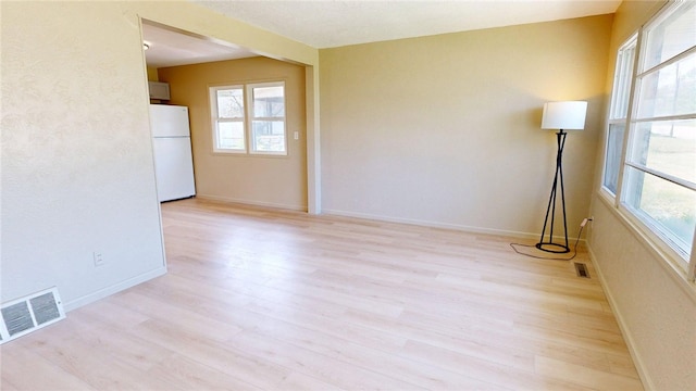 unfurnished room with baseboards, visible vents, and light wood finished floors