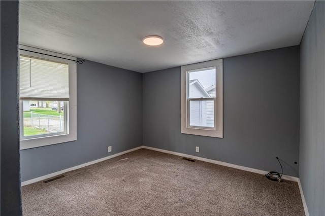 carpeted empty room with plenty of natural light, baseboards, visible vents, and a textured ceiling