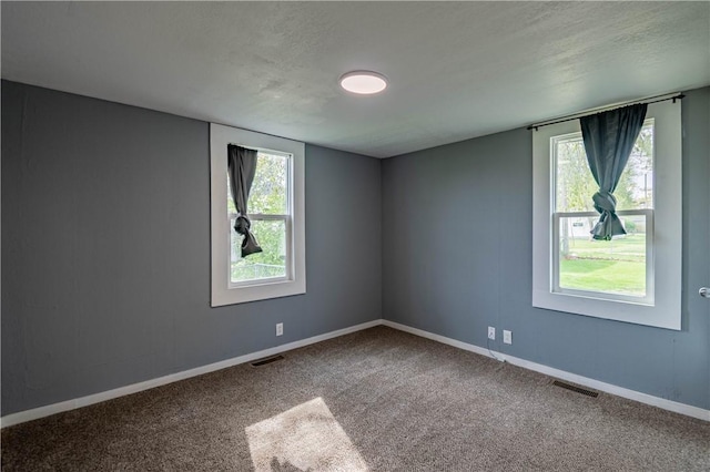 carpeted empty room featuring baseboards, visible vents, and a textured ceiling