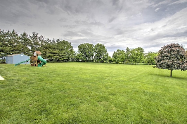 8898 Country Side Dr, Dalton City, IL 61925 - view of green lawn featuring a playground, a storage unit, and view of scattered trees