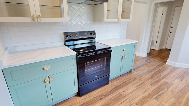 2550 Ivy Ln, Decatur, IL 62521 - kitchen featuring black electric range oven, blue cabinetry, light wood-style floors, tasteful backsplash, and glass insert cabinets
