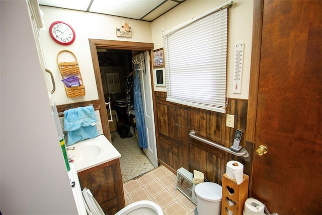 bathroom with wooden walls, a drop ceiling, and vanity