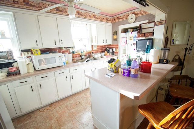 kitchen with a kitchen breakfast bar, white cabinetry, white appliances, and sink