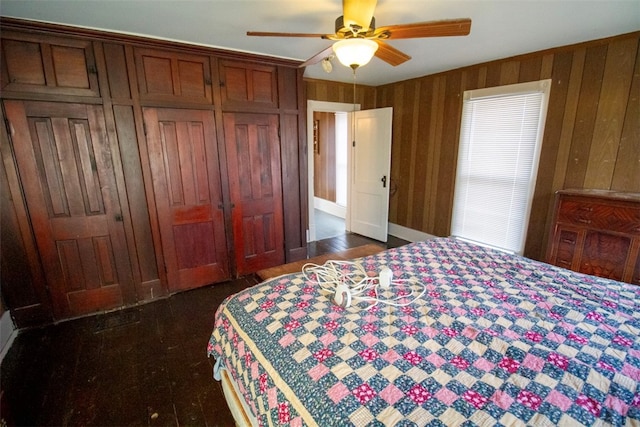 bedroom featuring ceiling fan, wooden walls, and a closet