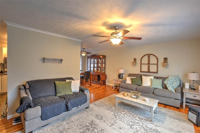 living room featuring hardwood / wood-style flooring, ornamental molding, and ceiling fan