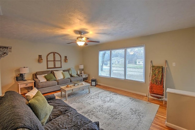 living room featuring ceiling fan, a textured ceiling, and light hardwood / wood-style floors