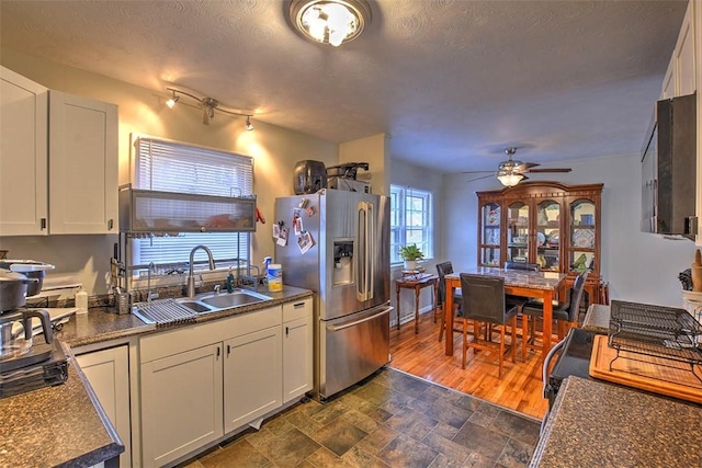 kitchen with stainless steel refrigerator with ice dispenser, sink, a textured ceiling, ceiling fan, and white cabinets