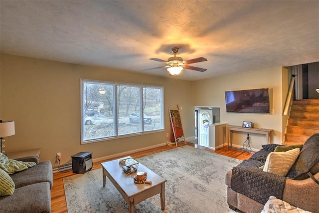 living room featuring hardwood / wood-style flooring, a textured ceiling, and ceiling fan