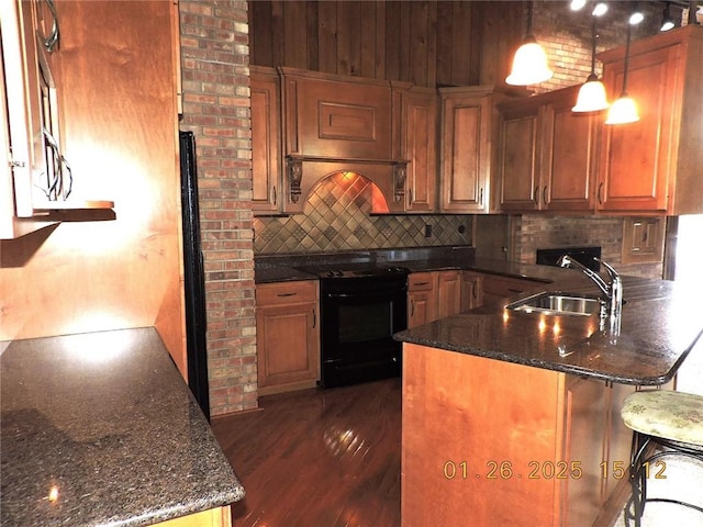 kitchen with decorative light fixtures, black electric range oven, dark stone countertops, sink, and kitchen peninsula