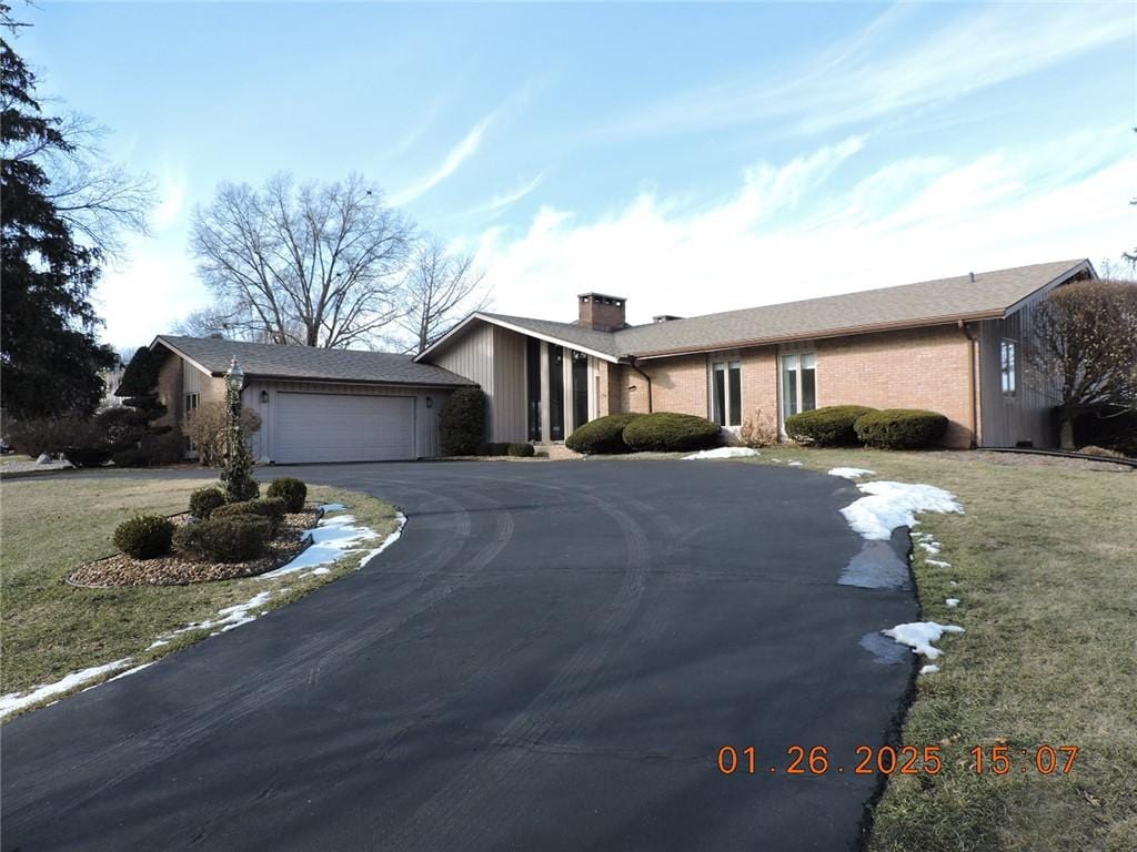 ranch-style home with a garage and a front lawn