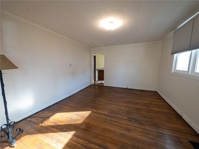 empty room with crown molding, wood finished floors, and visible vents