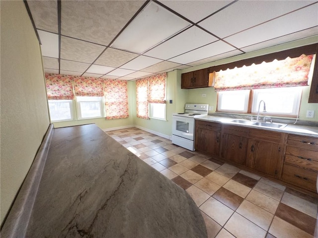 kitchen with a sink, plenty of natural light, a paneled ceiling, and white range with electric stovetop