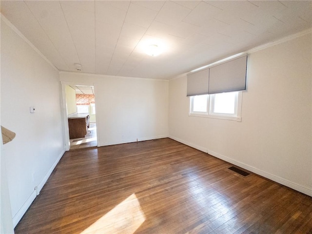 unfurnished room with baseboards, wood finished floors, visible vents, and ornamental molding