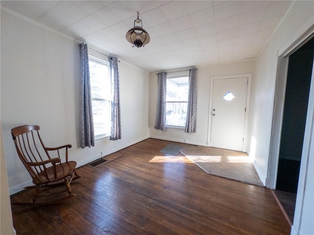 foyer entrance featuring crown molding, plenty of natural light, visible vents, and wood-type flooring