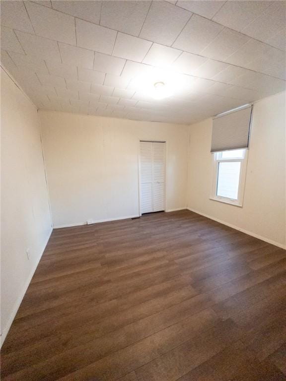 unfurnished room with dark wood-style floors and baseboards