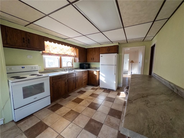 kitchen with white appliances, light countertops, a paneled ceiling, and a sink