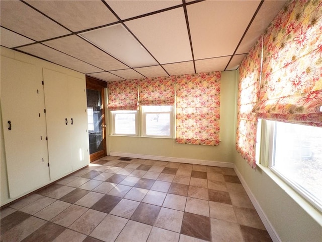 tiled empty room with a paneled ceiling and baseboards