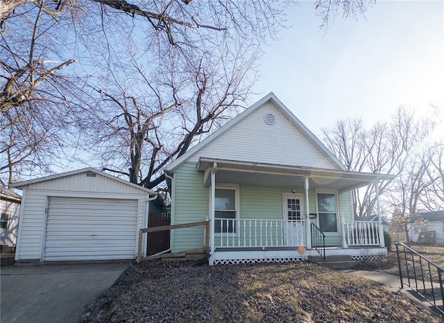 bungalow-style house with a porch, concrete driveway, a detached garage, and an outdoor structure