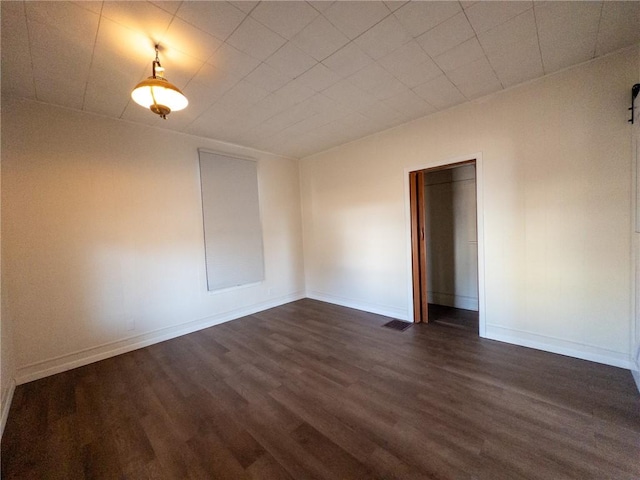 unfurnished room with visible vents, baseboards, and dark wood-style flooring