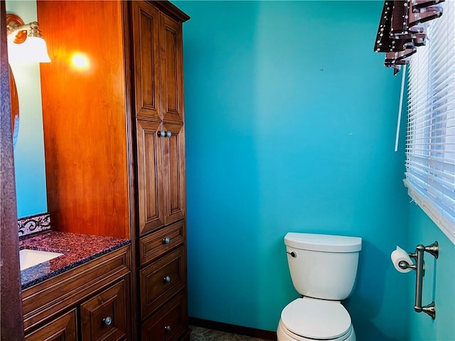 bathroom with toilet, baseboards, and vanity