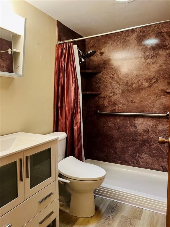 full bath featuring toilet, a stall shower, wood finished floors, and vanity