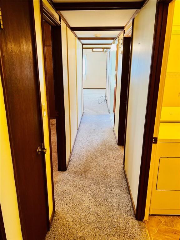 hall with light carpet and washer / clothes dryer