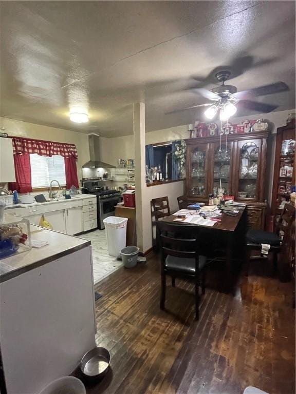 dining area with ceiling fan, dark hardwood / wood-style flooring, sink, and a textured ceiling