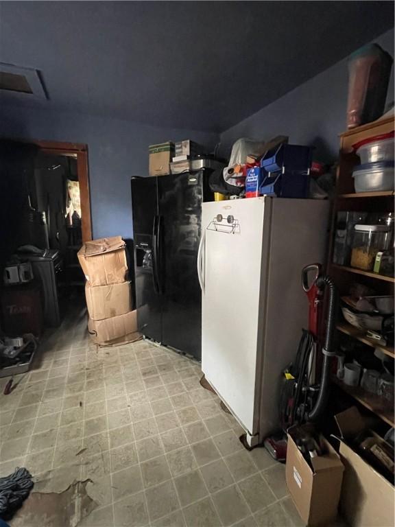 basement featuring black fridge and white refrigerator