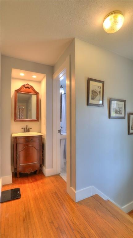 hall featuring baseboards, a sink, and light wood-type flooring
