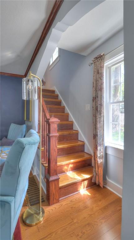 staircase with baseboards, wood finished floors, and a wealth of natural light