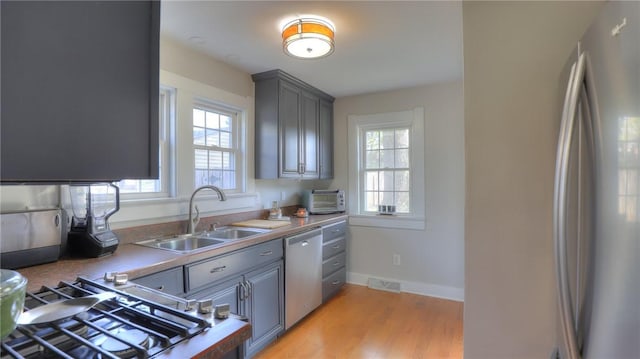 kitchen featuring stainless steel appliances, a sink, a wealth of natural light, and visible vents