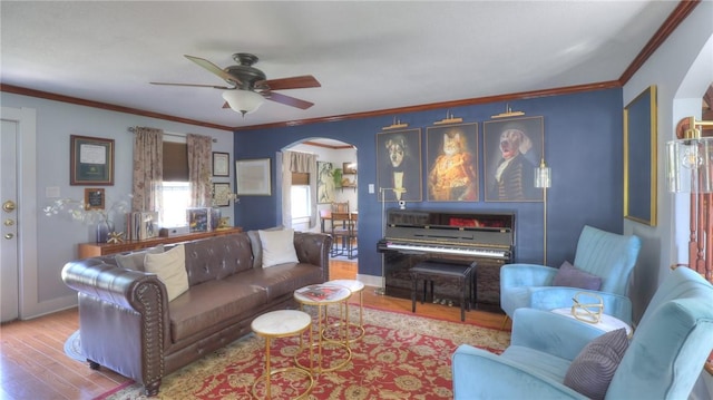living area with arched walkways, a ceiling fan, wood finished floors, and ornamental molding
