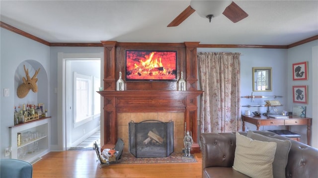 living room with ornamental molding, a ceiling fan, wood finished floors, and a fireplace