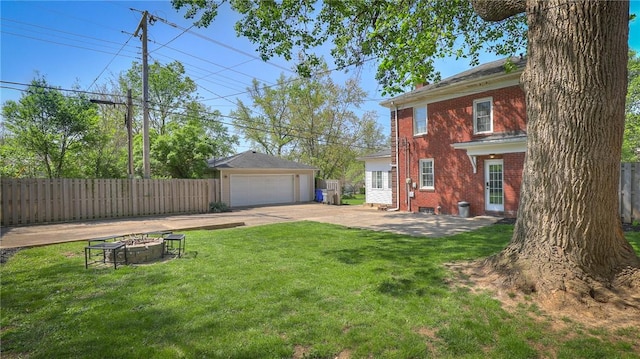 view of yard featuring fence, a detached garage, an outbuilding, and an outdoor fire pit