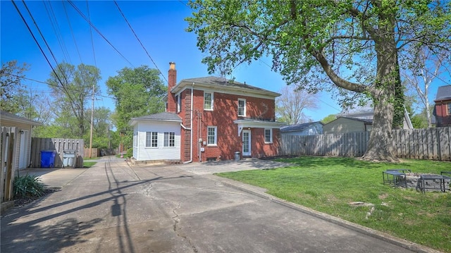 view of front of property with a front lawn, a fire pit, fence, a chimney, and brick siding