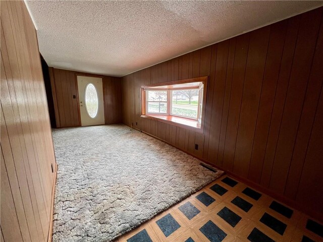 foyer with a textured ceiling and wood walls