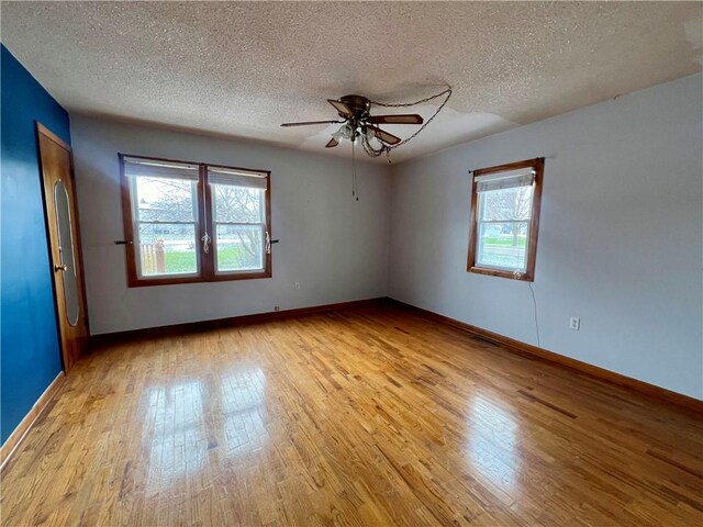 unfurnished room with ceiling fan, light wood-type flooring, a textured ceiling, and french doors