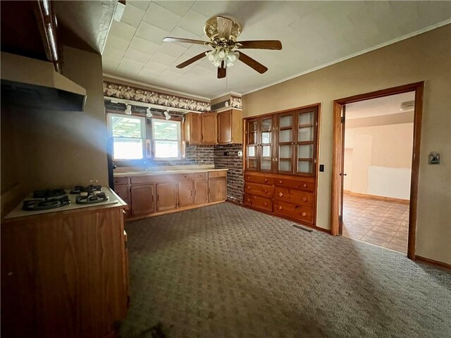 kitchen featuring dark carpet, ceiling fan, ornamental molding, and white gas stovetop