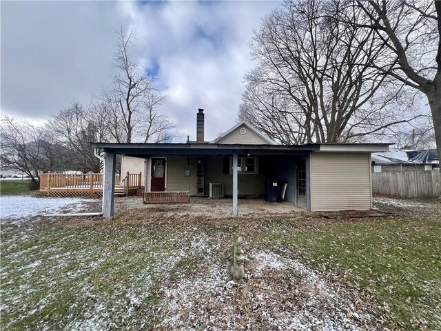 back of house featuring central AC, a deck, and a lawn