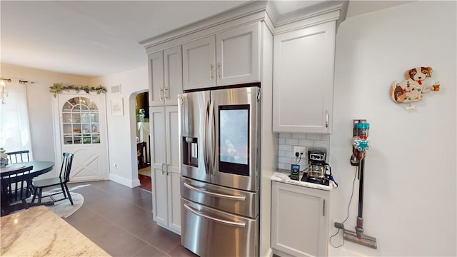 1805 N Gilbert St, Danville, IL 61832 - kitchen featuring light stone countertops, stainless steel refrigerator with ice dispenser, dark tile patterned floors, tasteful backsplash, and arched walkways
