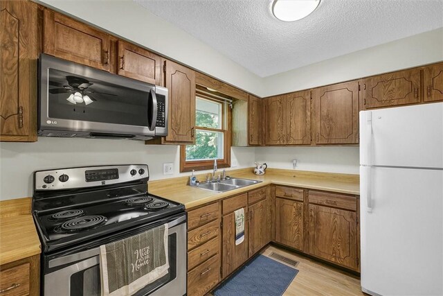 946 Foxcrest Dr, Charleston, IL 61920 - kitchen with appliances with stainless steel finishes, light countertops, a textured ceiling, brown cabinets, and light wood-style flooring