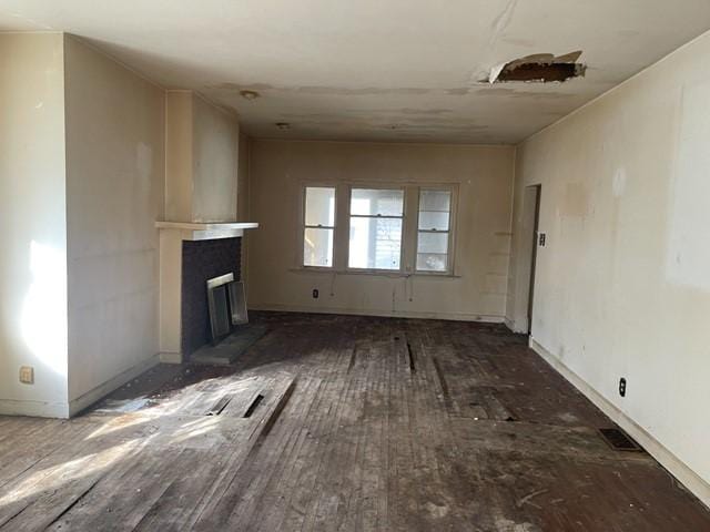 unfurnished living room with a fireplace with raised hearth and wood finished floors