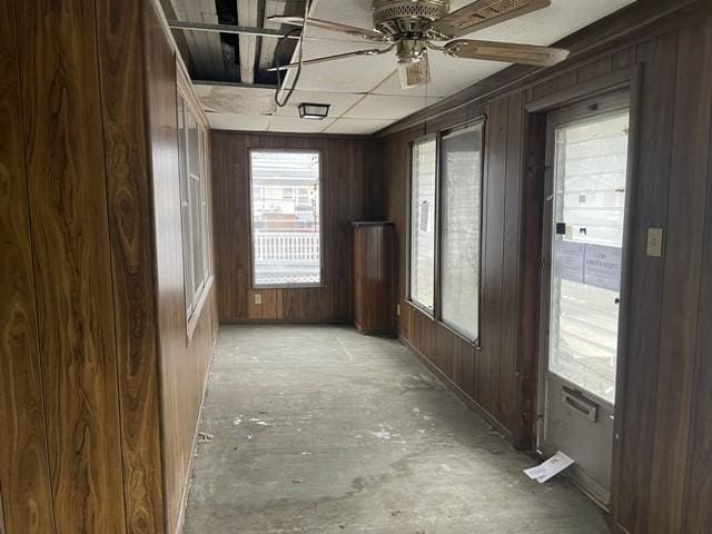 interior space with wood walls and ceiling fan