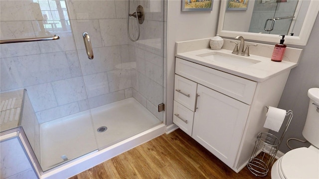bathroom with wood finished floors, a stall shower, toilet, and vanity