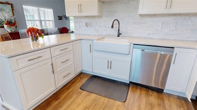 kitchen with dishwasher, a sink, white cabinets, a peninsula, and light wood-style flooring