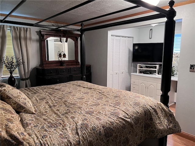 bedroom with crown molding, a closet, and hardwood / wood-style flooring