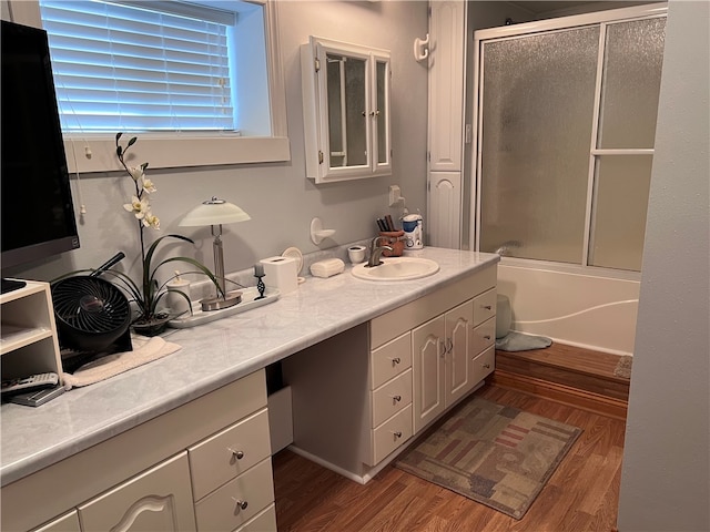 bathroom featuring wood-type flooring, vanity, and bath / shower combo with glass door